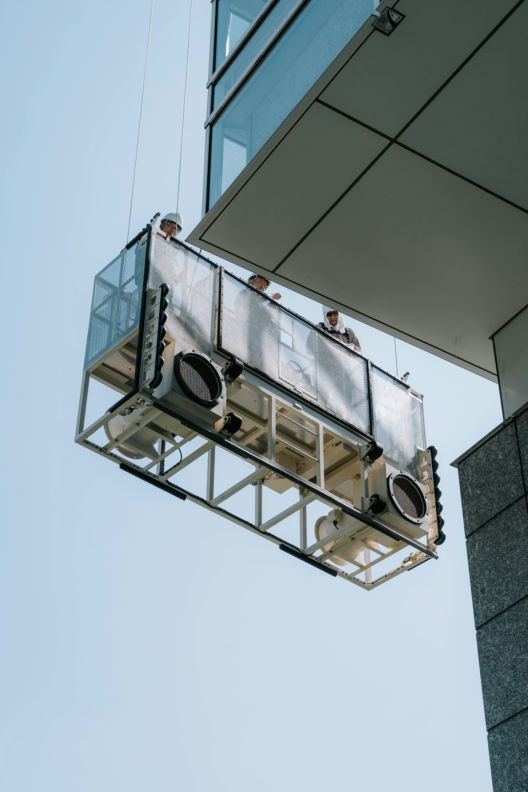 Workers on a suspended platform cleaning skyscraper windows